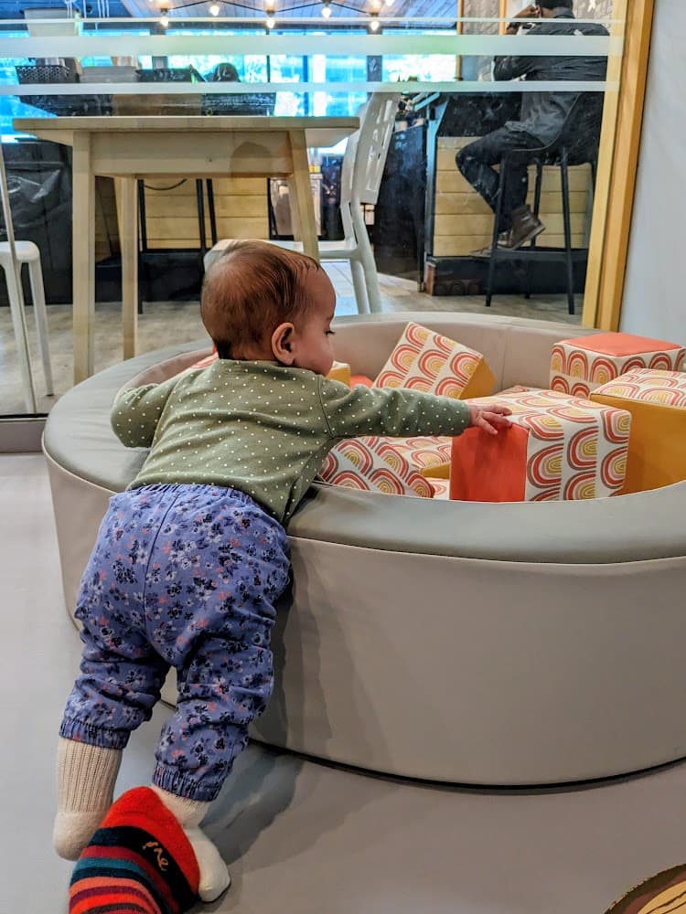 A small baby reaching into a soft foam play pit.